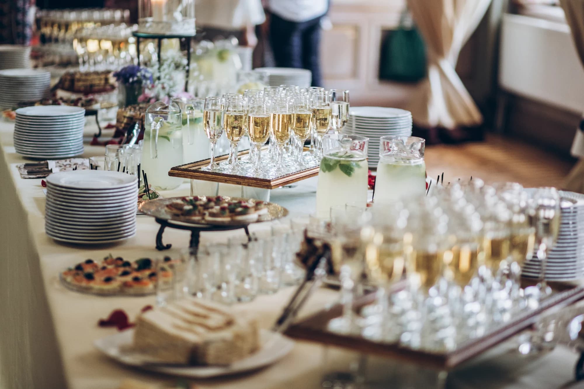 Gost uzima kanape sa buffet stola ukrašenog cvećem i poslužavnicima